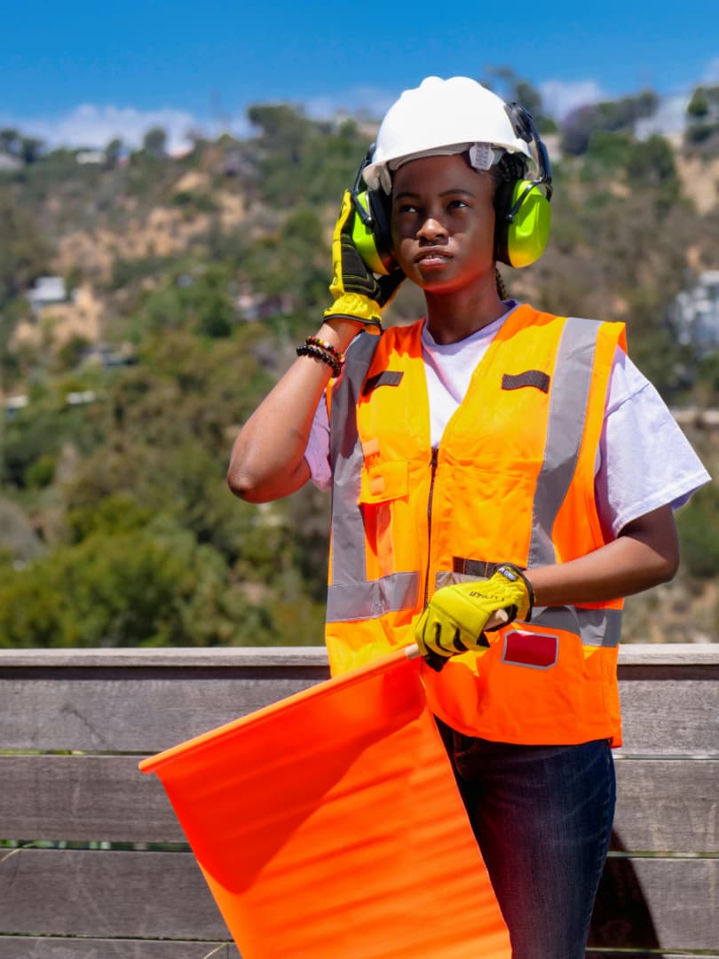 A construction worker wearing an orange reflective vest and holding an orange flag